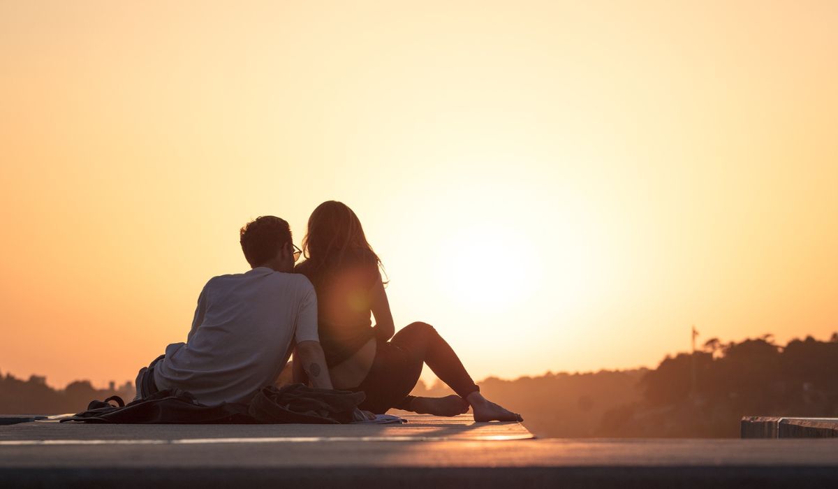 a young couple sitting outside watching sunset